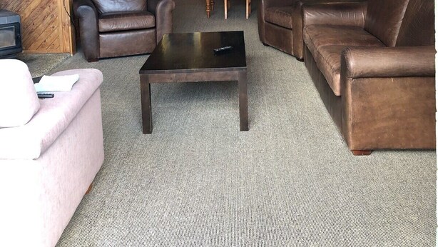 A cozy living room with leather sofas, a coffee table, and a TV. - The heart of Ohakune township with mountain views (Ohakune)