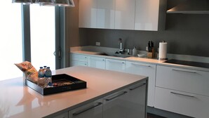 A modern kitchen with a central island, white cabinetry, and pendant lighting.