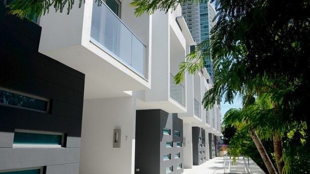 A modern building with a clean, minimalist design, featuring large windows and a flat roof.