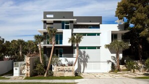 A modern two-story house with a flat roof, large windows, and a stone foundation.