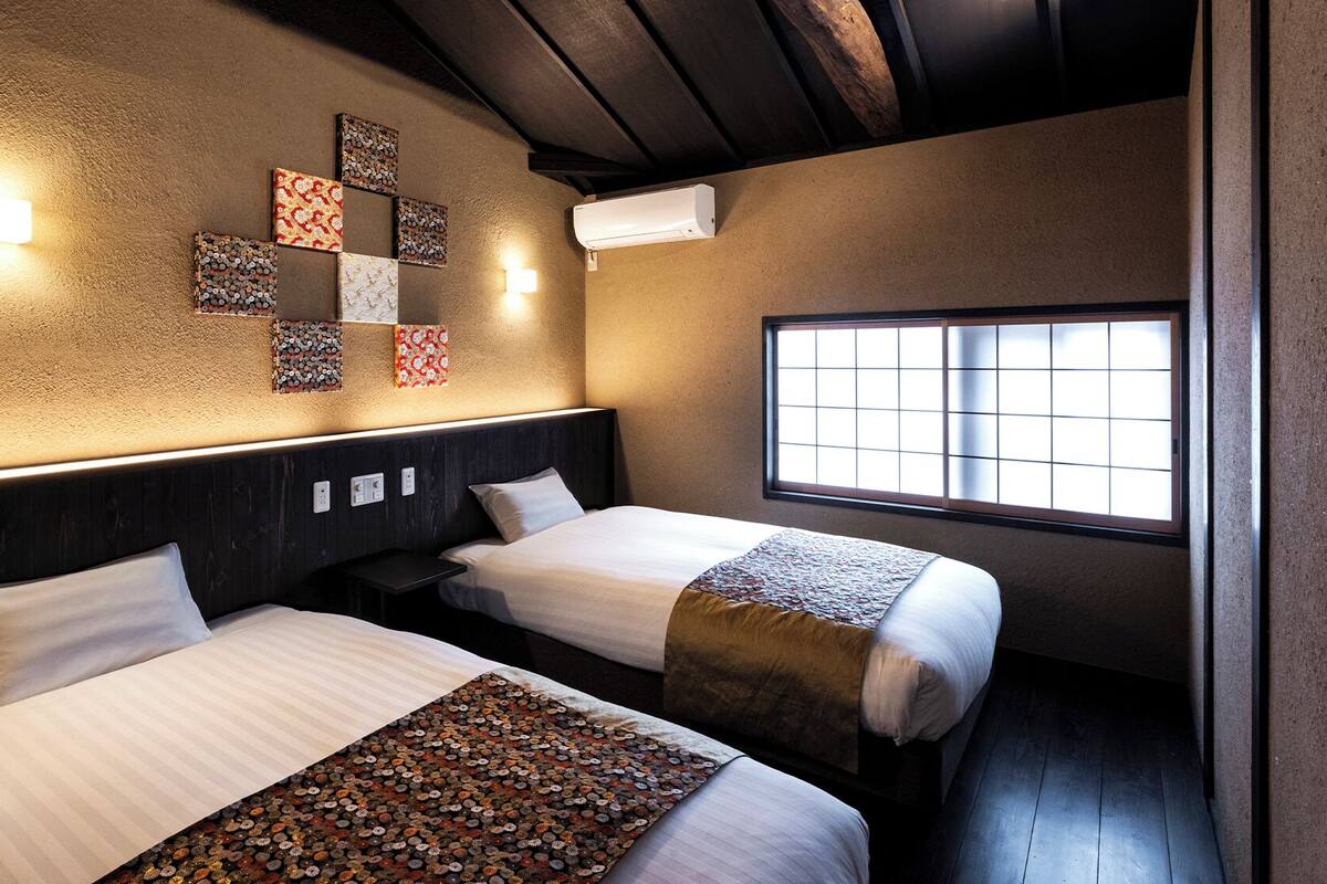 A hotel room with two beds, a window with a view, and decorative wall art.