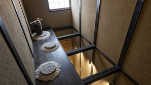 A narrow corridor with a wooden table featuring woven placemats and a small decorative item. - Rinn Premium Yae  (Kyoto)