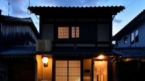 A traditional Japanese building with a tiled roof, a wooden entrance gate, and a lit lantern. - Rinn Premium Yae  (Kyoto)