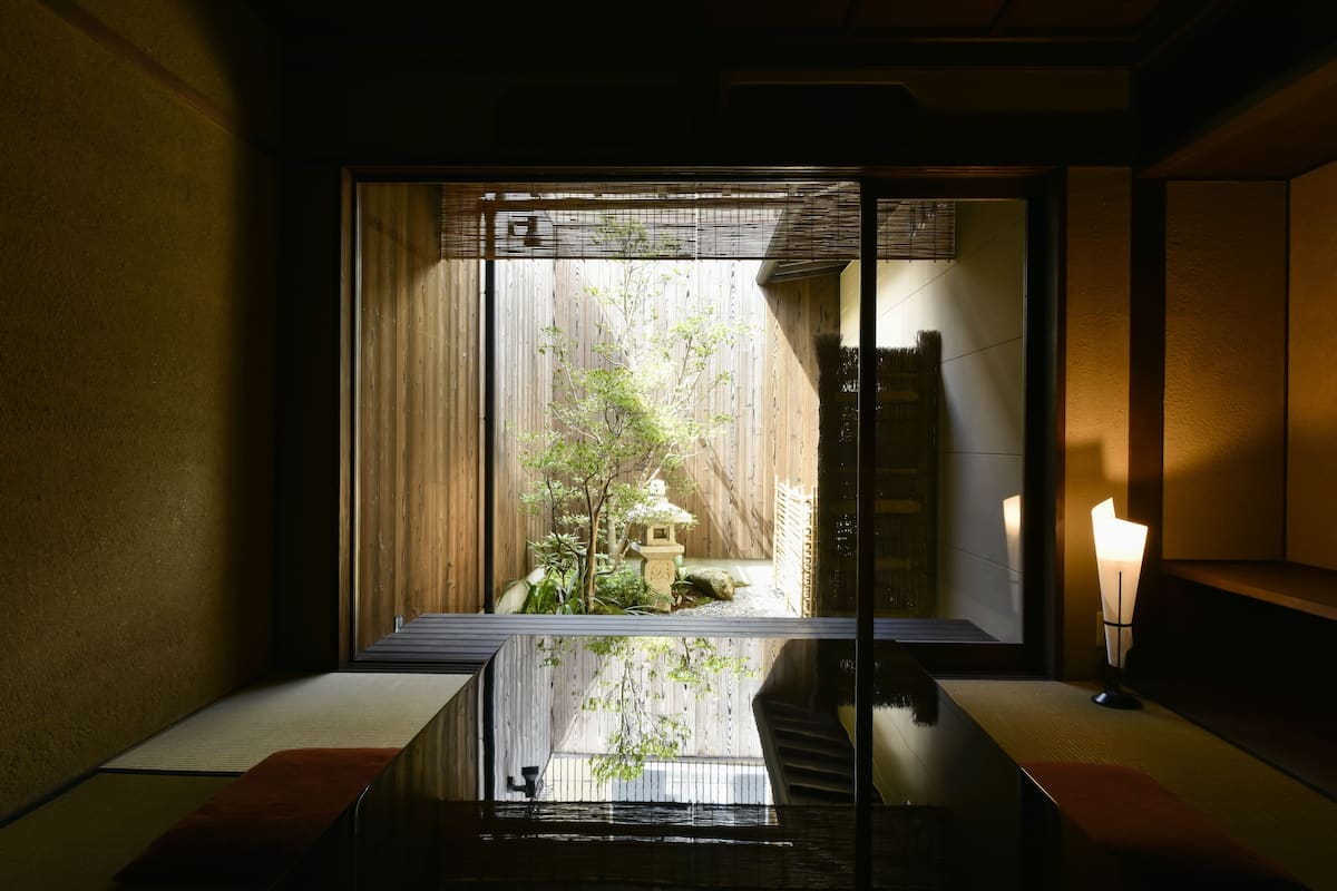 A traditional Japanese room with tatami flooring, a shoji screen, and a small garden view.