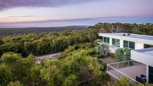 Una casa moderna con un balcón grande que da a un paisaje boscoso.