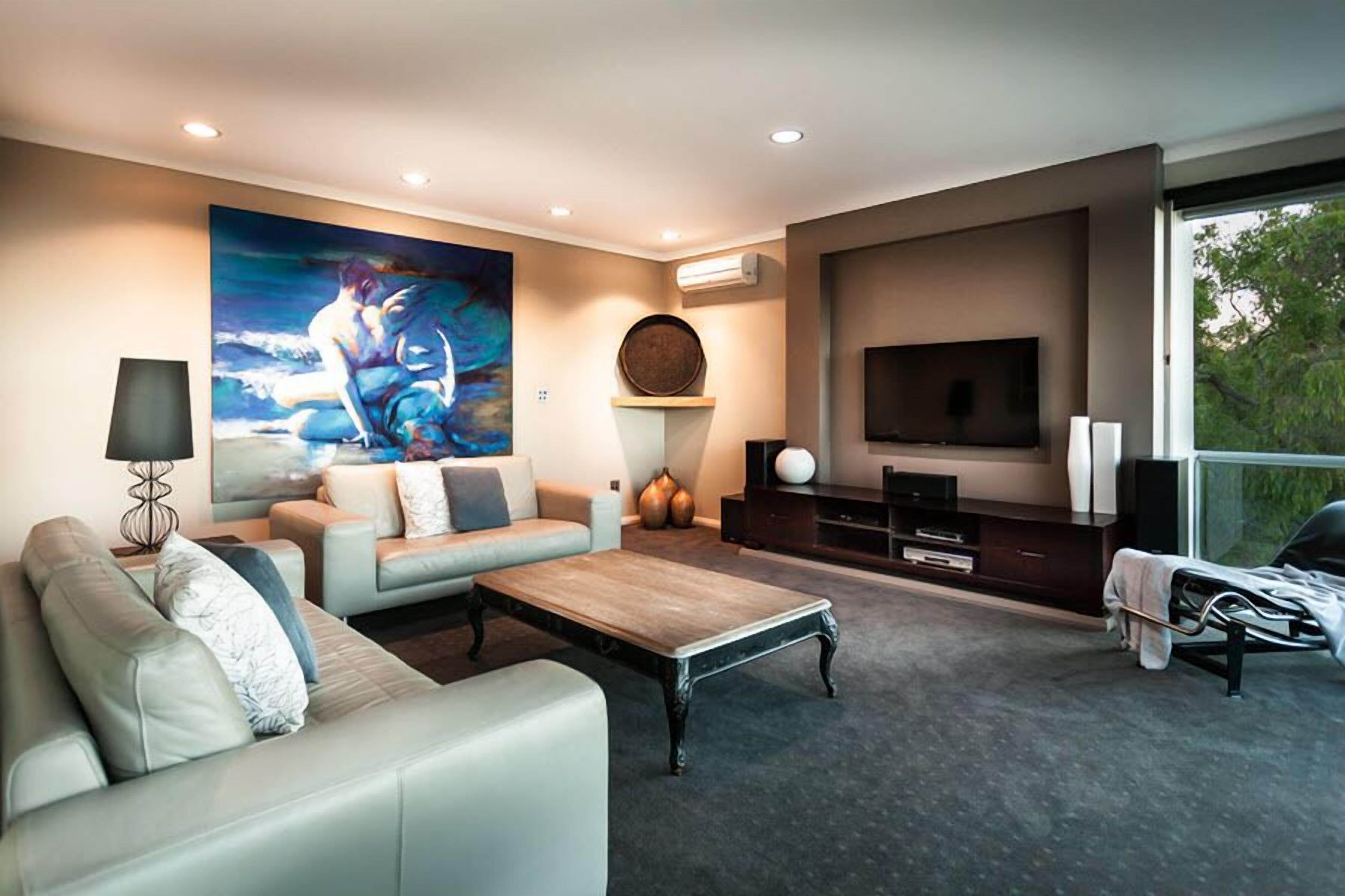 A modern living room with a large painting, a sofa, a coffee table, and a TV.