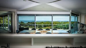 Una habitación moderna con un amplio ventanal que ofrece vistas al océano y al verdor.