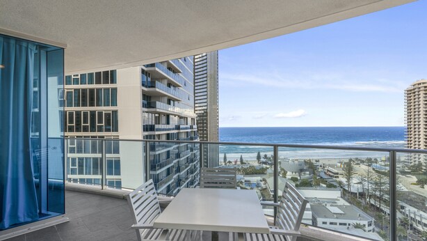 A balcony with a table and chairs, overlooking a beach and ocean. - Apartment 11504 is a holiday makers dream. Boasting a prime location (Surfers Paradise)
