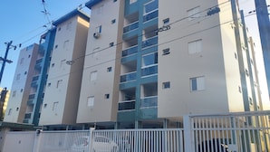 Un edificio residencial de varios pisos con balcones y un estacionamiento cerrado.