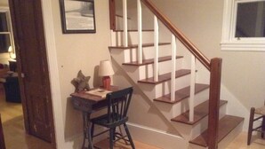 A staircase with wooden steps and a wooden handrail, leading to an upper floor.