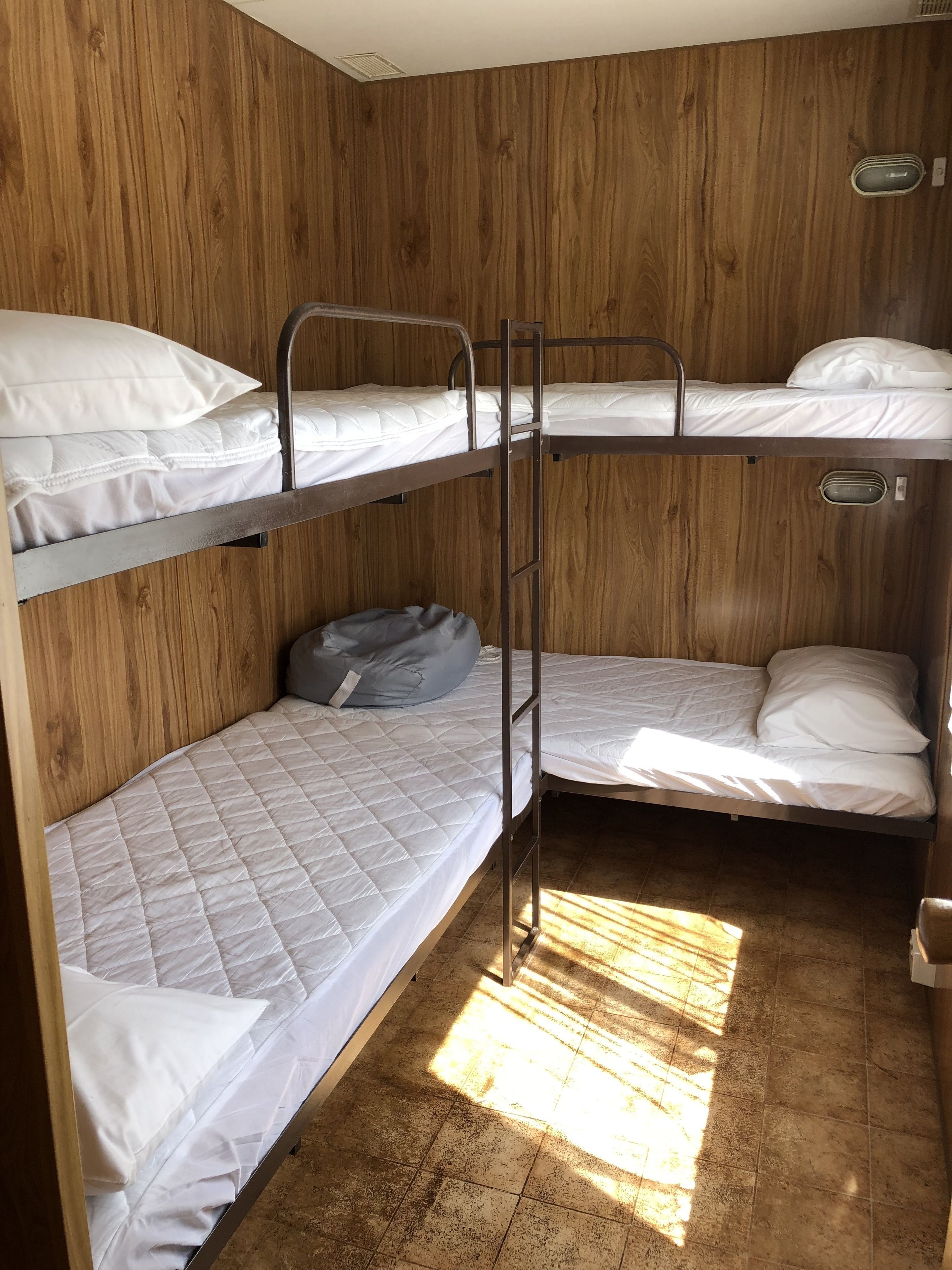 A bunk bed room with wooden walls and a tiled floor.
