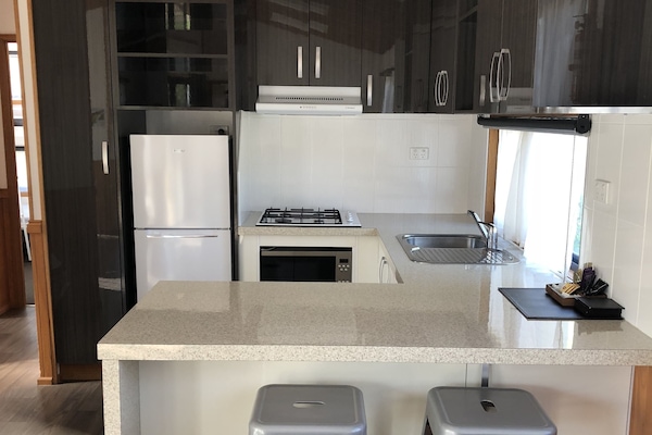 Huisje | Privékeuken | Een koelkast met diepvriezer, een microgolfoven, een kookplaat