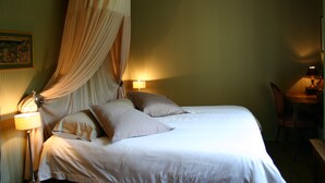 Ein Hotelzimmer mit einem Bett, zwei Nachttischlampen, einem Sessel und einem Schreibtisch.