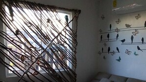 Una sala de estar con un sofá, un tapete colorido, un osito de peluche y una decoración de aves y mariposas.