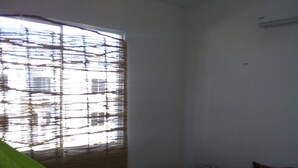 Un dormitorio con cama, ventana con persianas y una hamaca.