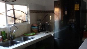 Una cocina con un lavamanos, un refrigerador y una ventana.