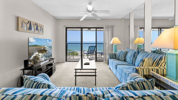Une chambre d’hôtel avec un balcon, une télévision, un canapé et une table basse.
