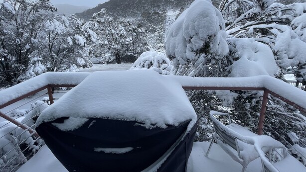 A snow-covered landscape with a car parked in the foreground and a mountainous background.