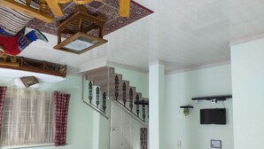 A spacious room with a large bed, a wooden ceiling with hanging lamps, a staircase with ornate railings, and a television mounted on the wall. - Spacious Beautifuly Furnished 3 Bedroom, Hall & Kitchen apartment. (Hyderabad)