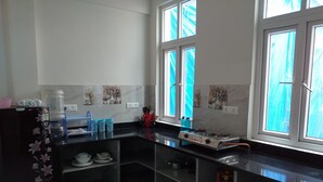 A kitchen with a black countertop, a gas stove, and a water dispenser. - Spacious Beautifuly Furnished 3 Bedroom, Hall & Kitchen apartment. (Hyderabad)