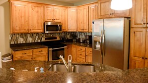 A kitchen with wooden cabinets, a stainless steel refrigerator, a microwave, and a sink. - Spacious 3 bed/2 bath Condo closest to Bridges Bay Amenities (Okoboji)