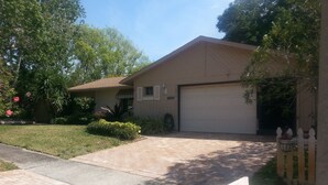 A residential house with a garage, a paved driveway, and a well-maintained lawn.