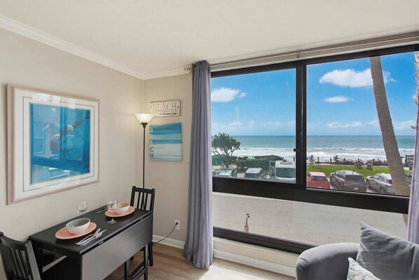 Una habitación con una mesa de comedor, sillas, una lámpara y vista a la playa.