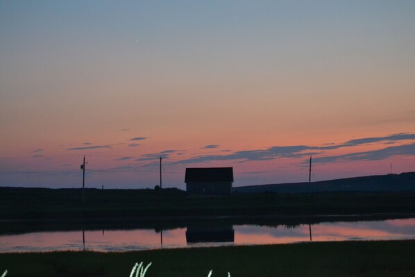 A house by a calm lake at dusk with a clear reflection.