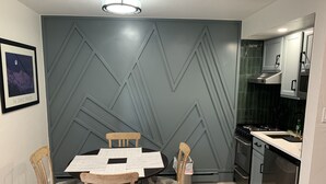 A modern kitchen with a grey geometric wall design, a dining table with chairs, and a stainless steel refrigerator. - 1 min. walk to Ski Lift/Gondola, shopping & dining! Perfect location!New Remodel (Vail)