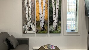 A living room with a gray sofa, a coffee table with remotes, and three birch tree paintings on the wall. - 1 min. walk to Ski Lift/Gondola, shopping & dining! Perfect location!New Remodel (Vail)