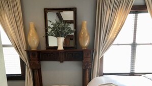 A bedroom with a bed, a bench, a mirror, and two vases. - Location, Location, Location!  Carriage House in Historic Old NE District (St. Petersburg)