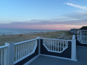 A beach view from a balcony with a white railing, sandy beach, and ocean in the background. - LBI Oceanfront. Beautiful! Views galore. Dine overlooking the dunes. (Beach Haven Crest)