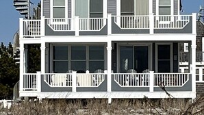 A two-story house with a balcony on the second floor, a covered porch on the first floor, and a spiral staircase on the left side. - LBI Oceanfront. Beautiful! Views galore. Dine overlooking the dunes. (Beach Haven Crest)