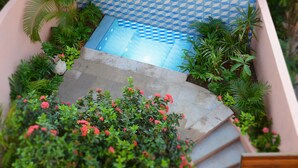 A pool with a geometric tile pattern, surrounded by lush greenery and pink flowers. - Casita Mimas: High design, great views, romantic retreat  (Sayulita)