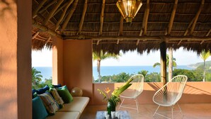 A thatched-roof balcony with a sofa, two chairs, and a table with drinks. - Casita Mimas: High design, great views, romantic retreat  (Sayulita)