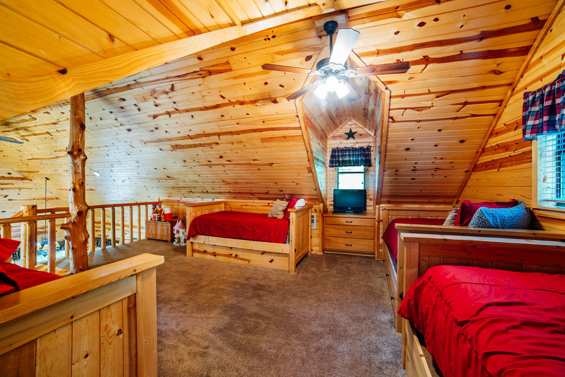Ein gemütliches Blockhaus mit zwei Holzbett und einem Deckenventilator sowie einem Fernseher.