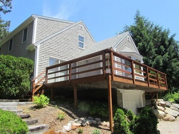 A two-story house with a wooden deck and a stone pathway leading to the front door.