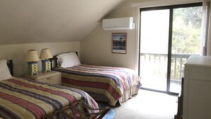 Ein Schlafzimmer mit zwei Betten, einem Fenster und einem Deckenventilator.