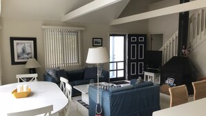 Ein gemütliches Wohnzimmer mit einem weißen Tisch, einem blauen Sofa und einem schwarzen Kamin.