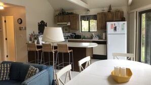 Eine Küche mit Holzausstattung, einem weißen Kühlschrank und einem Essbereich mit Tisch und Stühlen.