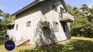 Eine Holzhütte mit Balkon, kleiner Terrasse und Garage.