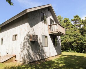 Una cabaña de madera con balcón, una pequeña terraza y un garaje.