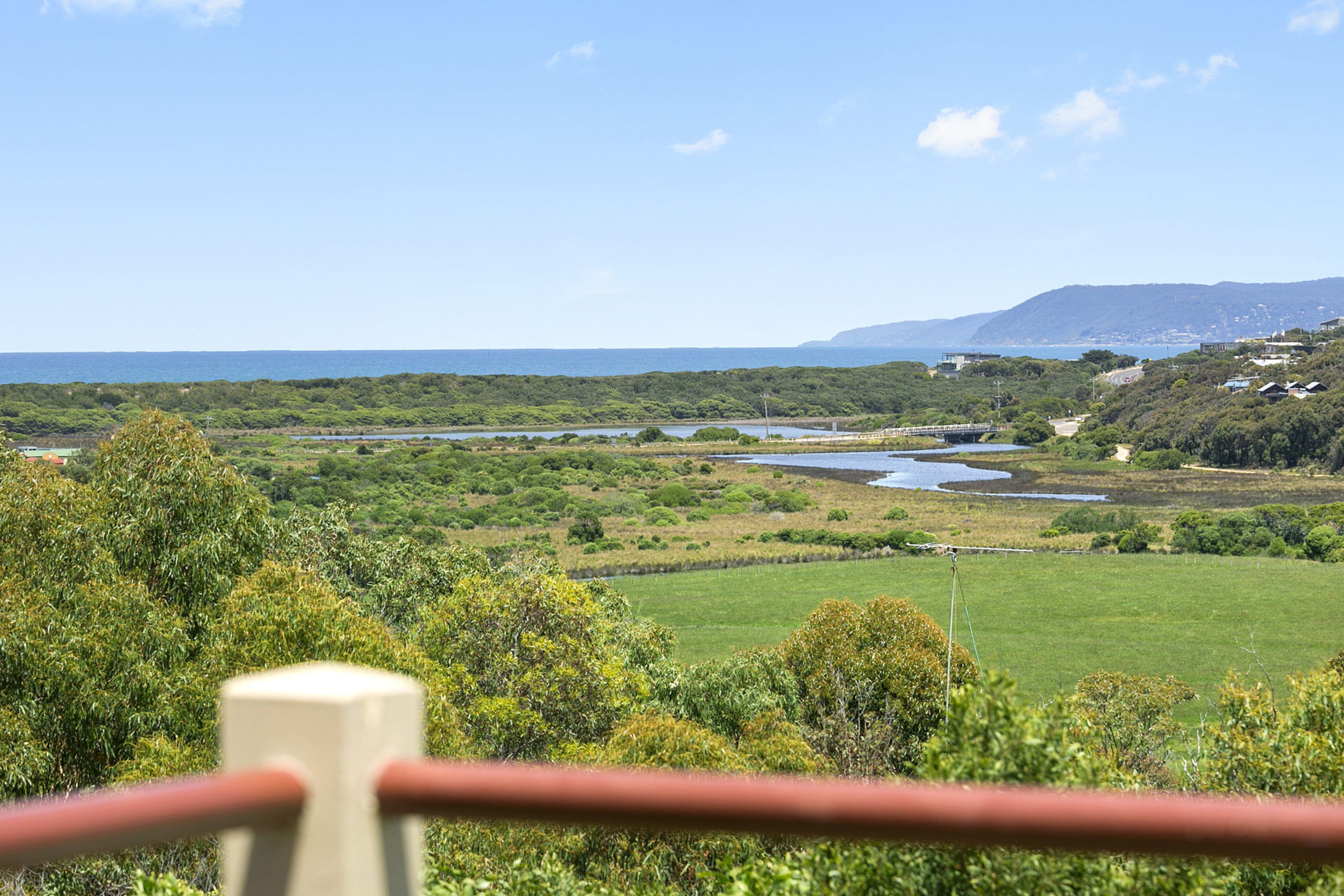 Eine Küstenlandschaft mit Blick auf das Meer, eine Brücke und hügeliges Gelände mit verstreuten Gebäuden.