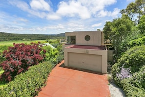 A modern building with a garage door, surrounded by lush greenery and a clear sky.