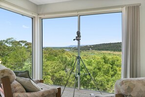 A room with large windows offering a view of a green landscape and a tripod in the center. - Panoramic Views (Aireys Inlet)