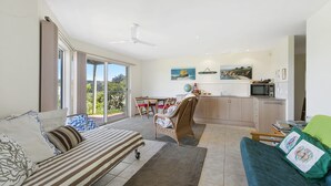 A spacious living area with a sofa, a dining table, and a kitchen area. - Panoramic Views (Aireys Inlet)