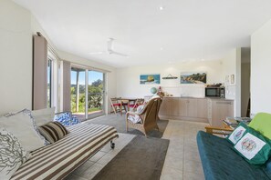A spacious living area with a sofa, a dining table, and a kitchen area. - Panoramic Views (Aireys Inlet)