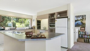 A modern kitchen with a central island, built-in appliances, and a view of the outdoors. - Panoramic Views (Aireys Inlet)