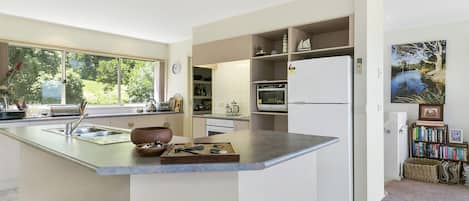 A modern kitchen with a central island, built-in appliances, and a view of the outdoors.