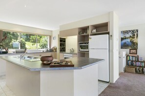 A modern kitchen with a central island, built-in appliances, and a view of the outdoors. - Panoramic Views (Aireys Inlet)